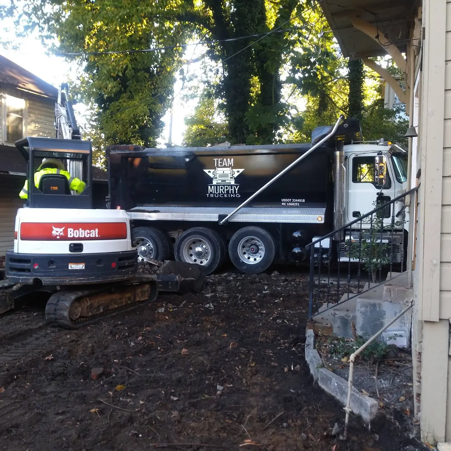 A truck is parked in the dirt near a tree.