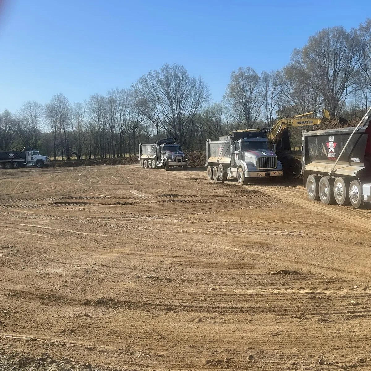 A group of trucks parked in the dirt.