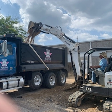 A dump truck is being loaded with dirt.