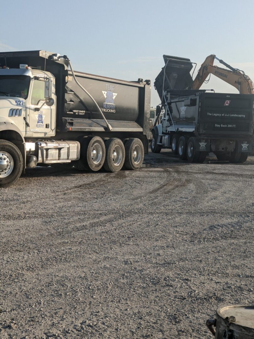 A dump truck is parked in the middle of a gravel lot.